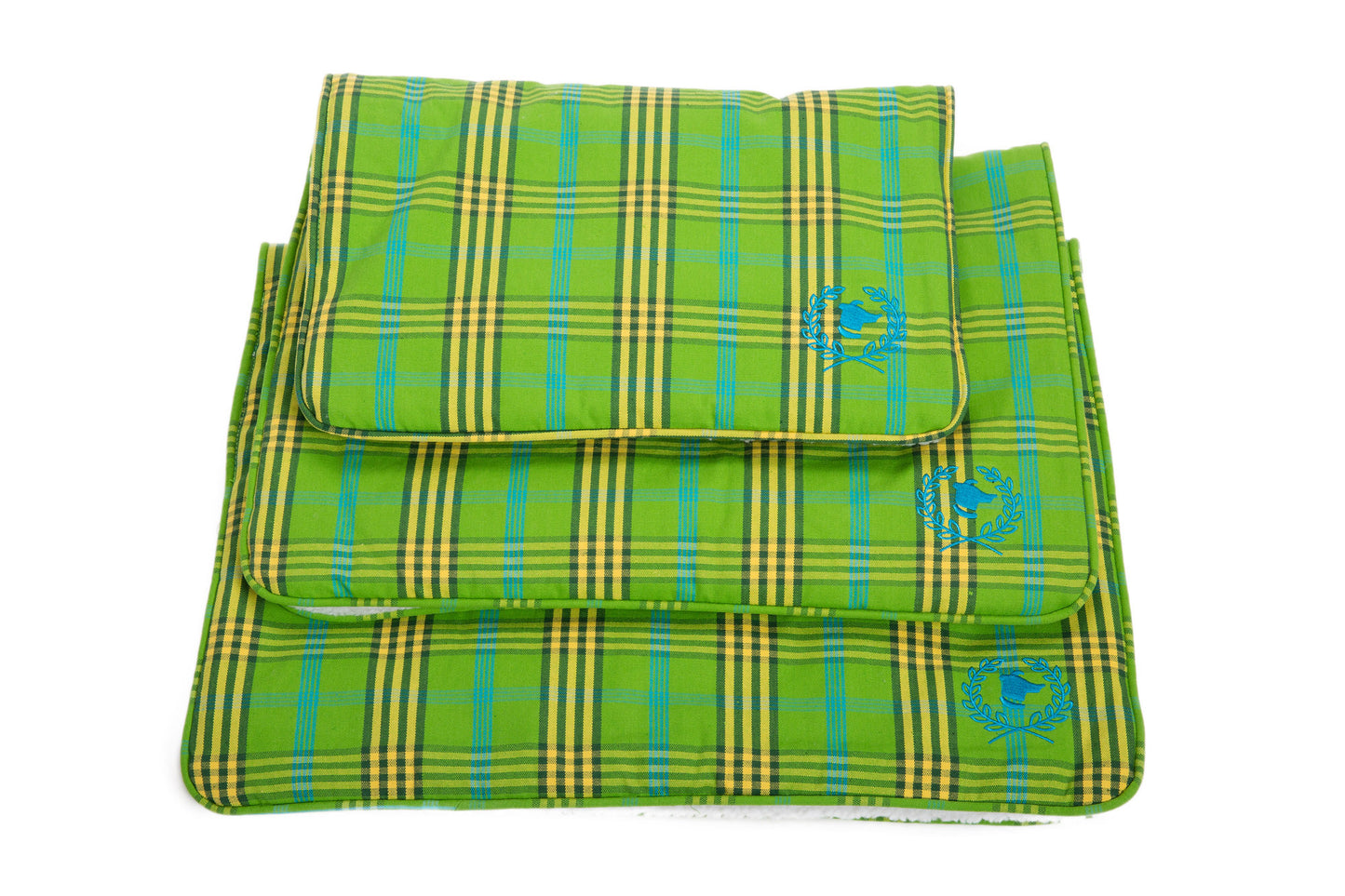 Stack of green plaid dog crate mats in various sizes with the brand 'Canine Styles' visible on the corner.