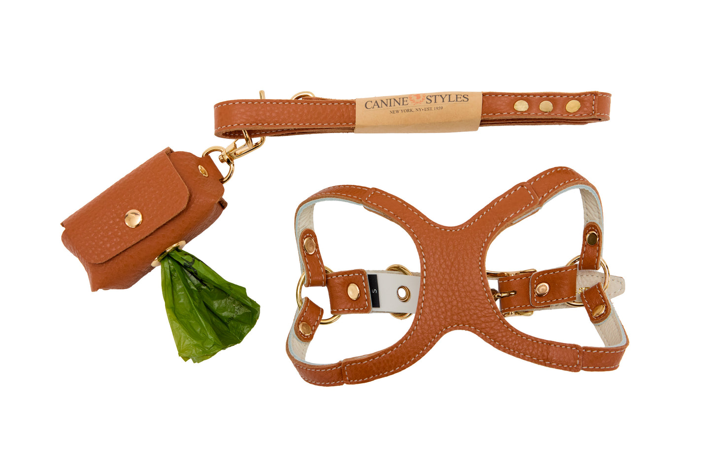 Brown leather dog lead, harness, and waste bag holder on a white background