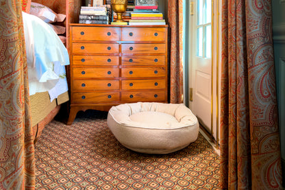 Dog bed in a room with wooden dresser and patterned curtains