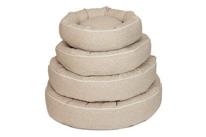 A stack of beige cotton canvas dog beds in various sizes with a round shape and raised edges.