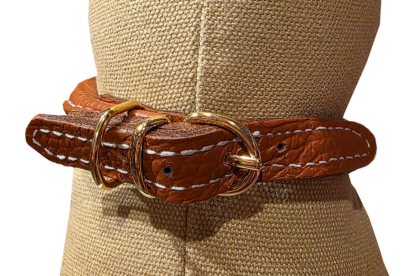 Brown leather belt with gold buckle on a mannequin wearing a beige hat.
